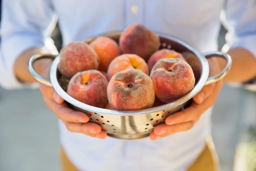 Un homme qui tient un bol de des pêches de vigne congelées