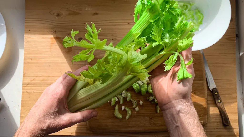 Une personne qui tient des céleris branches avec des feuilles