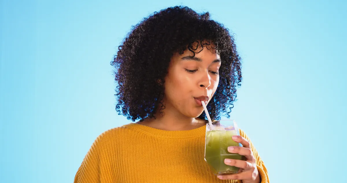 Une jeune femme qui boit du jus detox ce céleris branche