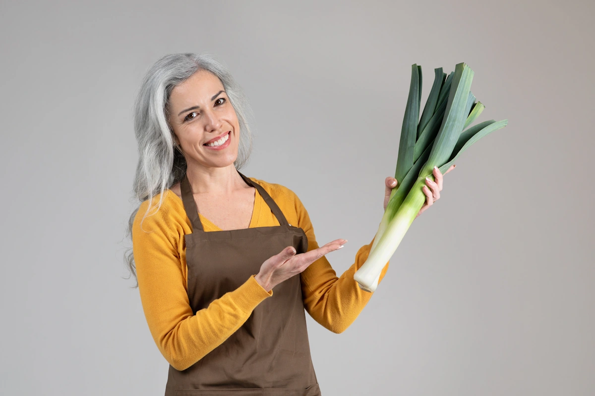 Une femme qui tient des poireaux