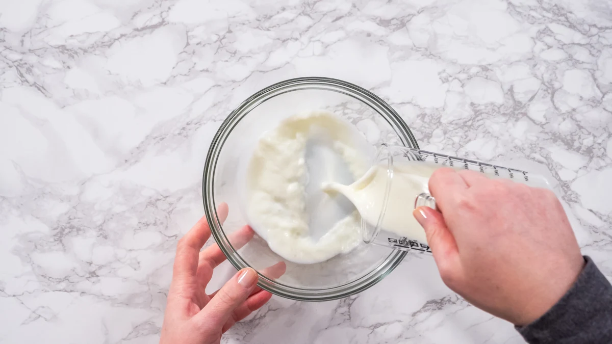 Une personne qui verse de la crème liquide dans un bol en verre
