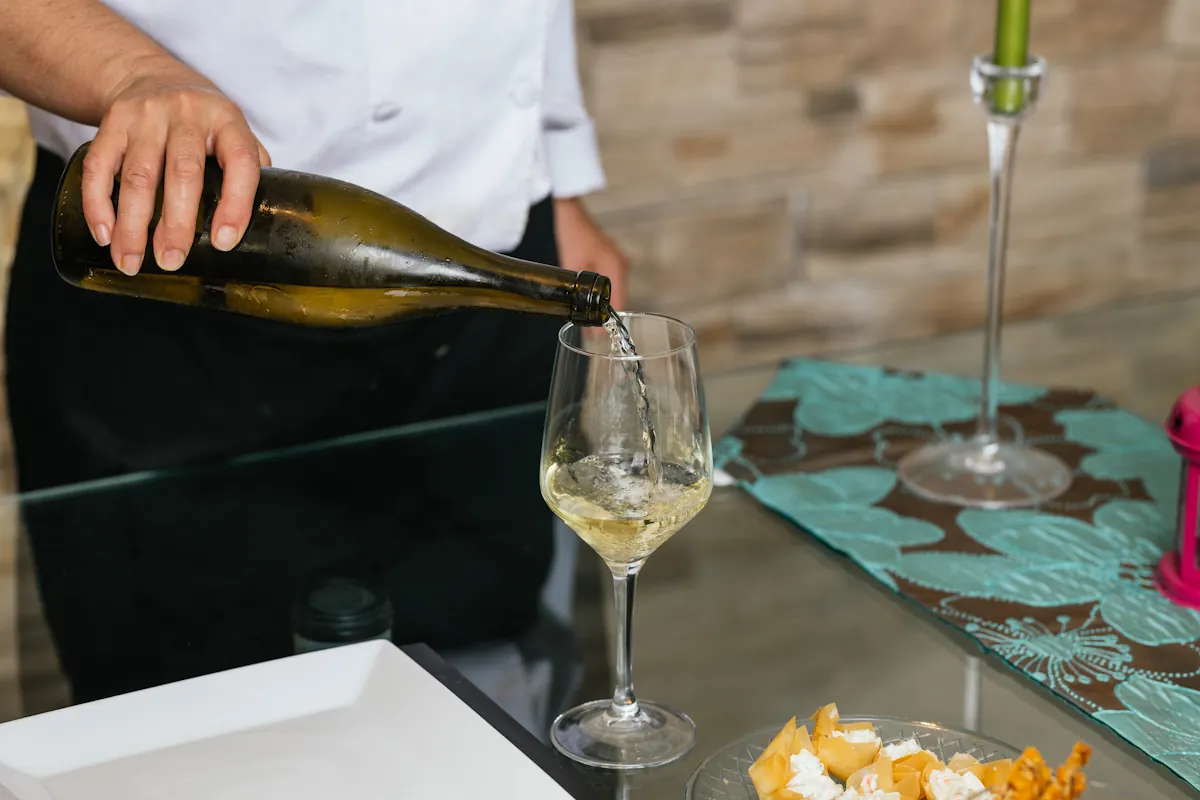 Une personne qui sert du vin blanc dans un verre