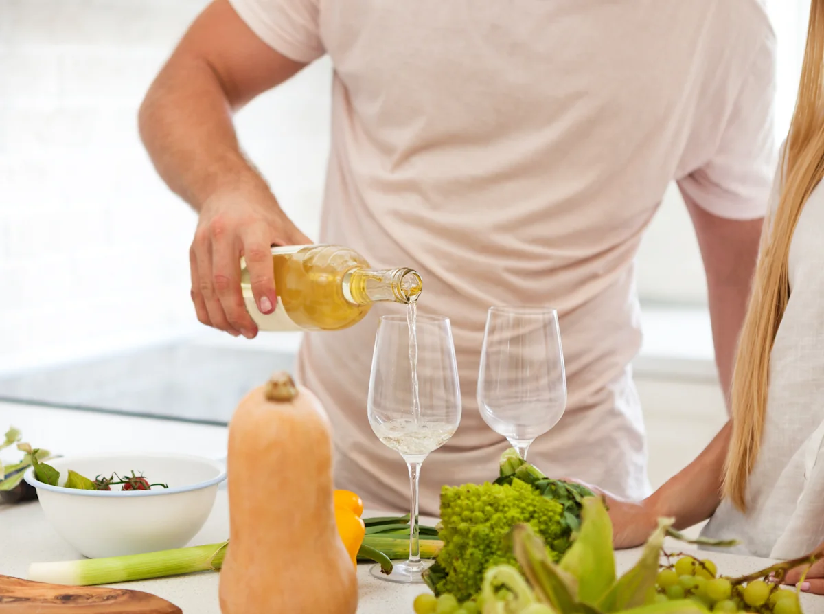 un homme qui sert un verre de vin blanc