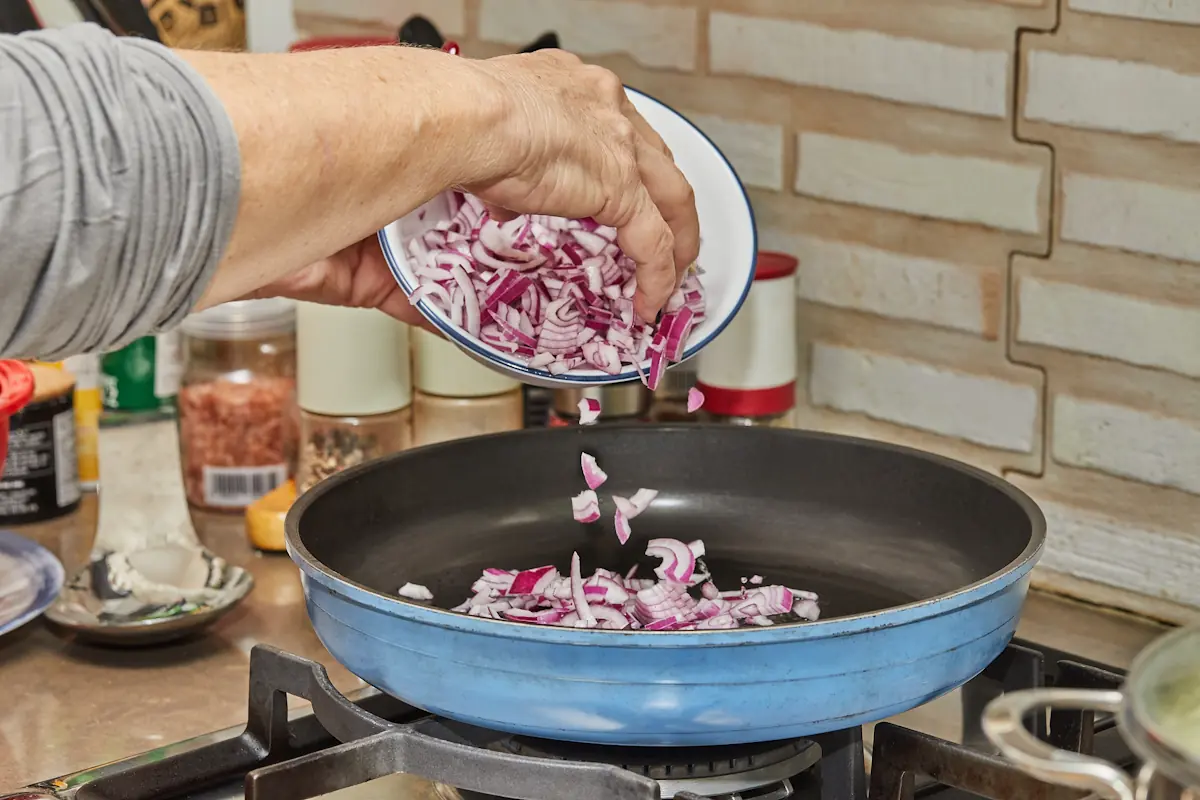 Une personne qui prépare confit d'oignons