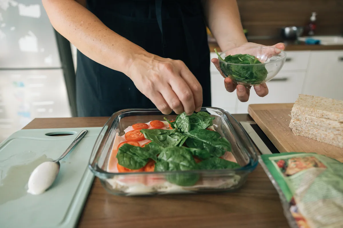 une personne qui prépare un plat d'épinard frais et champignons