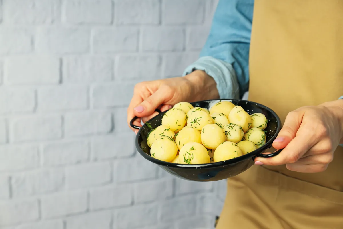 Une personne qui tient un plat de pommes de terre vapeur
