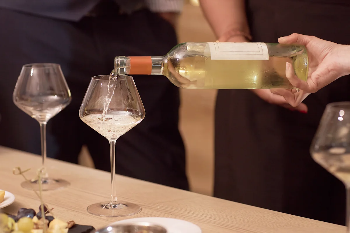 Une personne qui sert du vin blanc à table